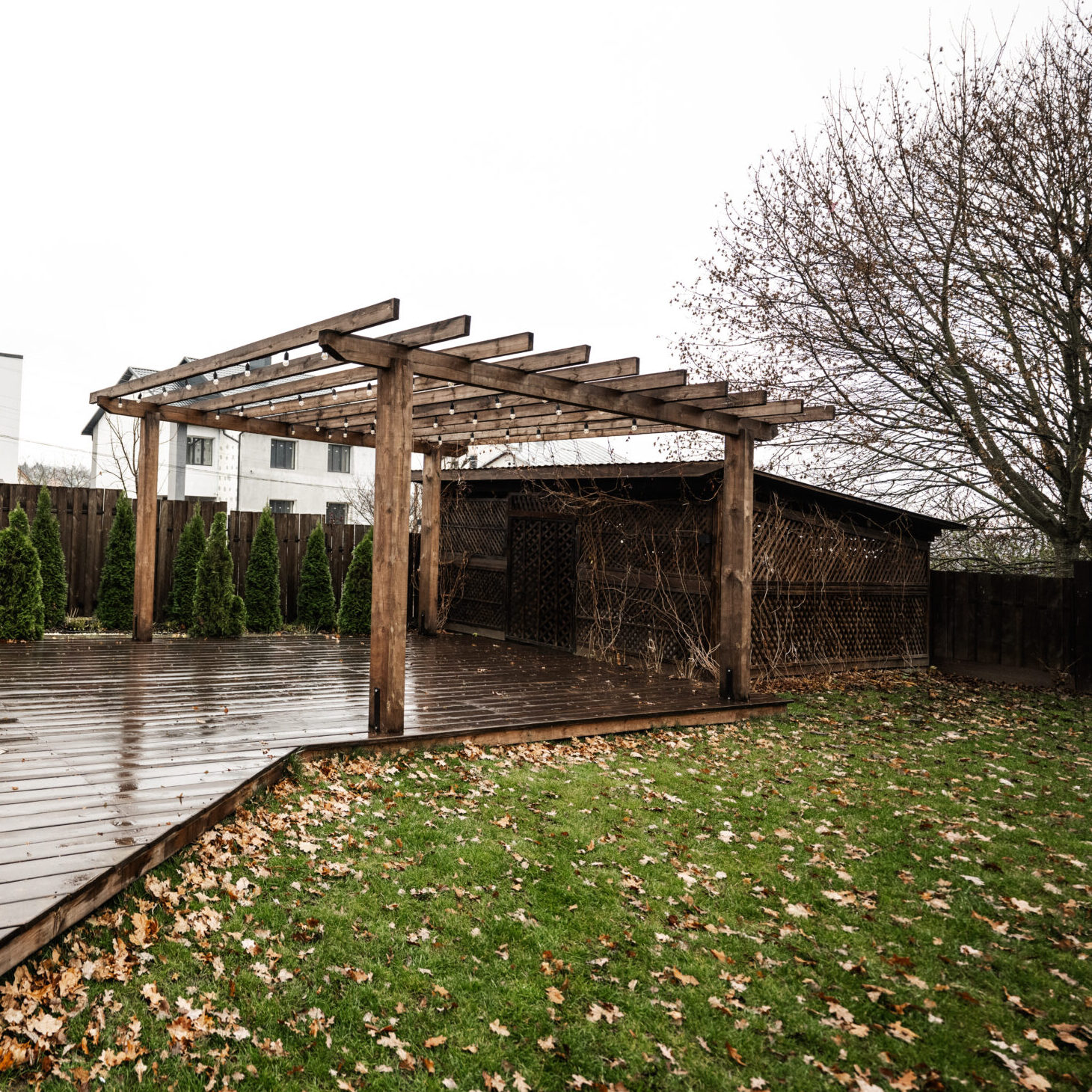 Stainless steel metal gas outdoor patio heater with wooden chairs and pot with flowers at wet terrace. Place to relax.